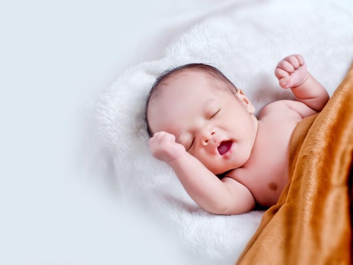 Baby Lying On White Fur With Brown Blanket