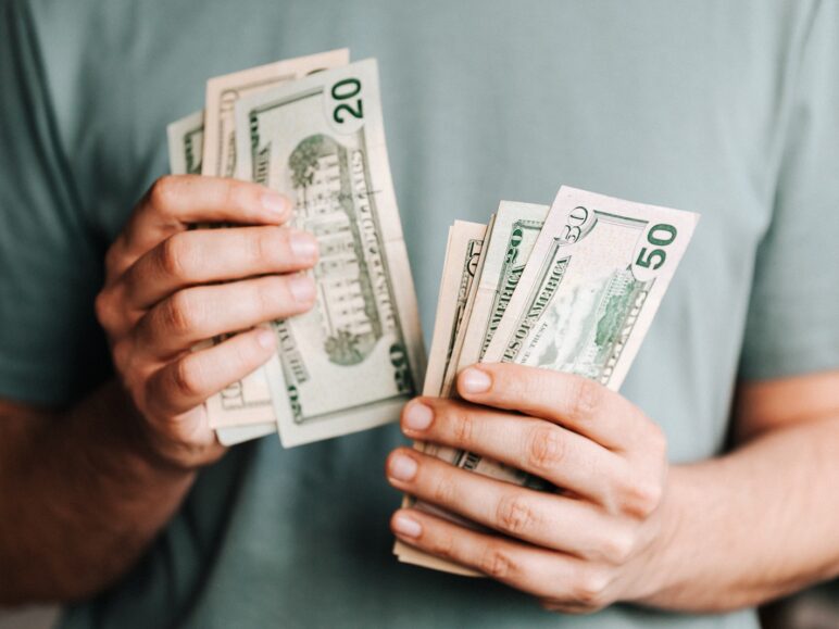 Crop man counting dollar banknotes